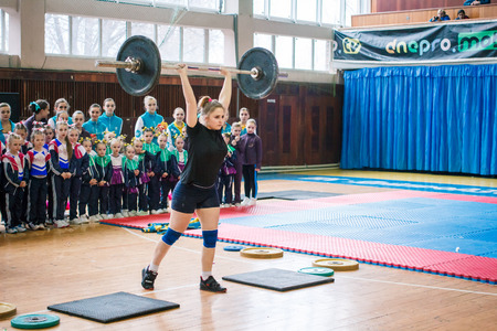 Kamenskoye, Ukraine - March 9, 2017: indicative performance of weightlifters at the championship in cheerleading,young girl lifts a heavy barbell, barbell weight - 60 kgのeditorial素材