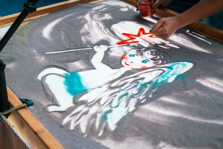 Sand animation, drawing sand closeup, girl drawing an angel on the sandの写真素材
