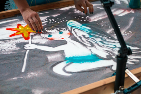 Sand animation, drawing sand closeup, girl drawing an angel on the sandの写真素材