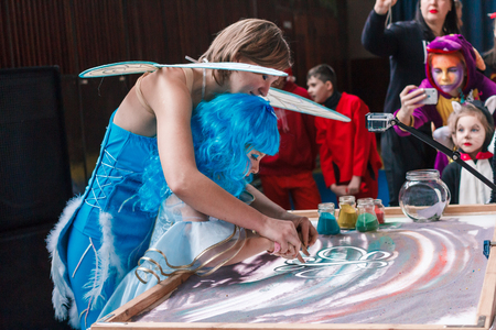 Kamenskoye, Ukraine - December 26, 2016: Christmas party for federation of cheerleading in Kamenskoye, woman draws on sand, sand animation, sand is pouring from his handsのeditorial素材