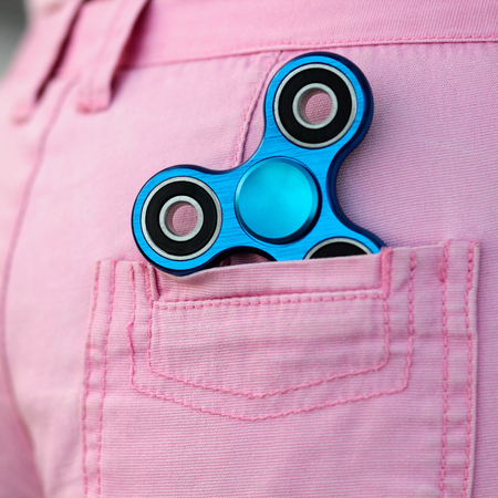 Blue metal popular fidget spinner in the back pocket of pink jeans shorts, anxiety relief toy, anti stress and relaxation fidgets の写真素材