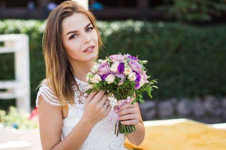 girl holding flowers in hands, young beautiful bride in white dress holding wedding bouquet, bouquet of bride from rose cream spray, rose bush, rose purple Memory Lane, violet eustoma, eucalyptusの写真素材