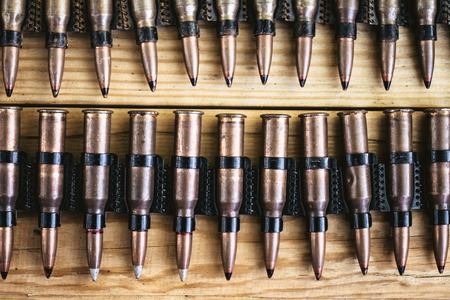 machine gun ammo on a wooden table, bullet belt, bandoleer, chain of ammo on wooden...