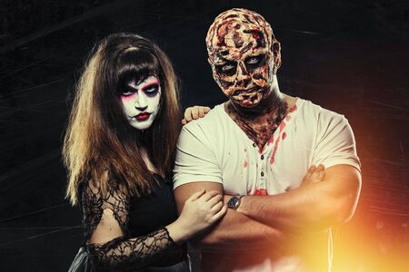 scary man with a face burn with a witch on a black background, zombie and a dead bride on a halloween carnival, couple with halloween makeup on black background, halloween face art, halloween conceptの写真素材
