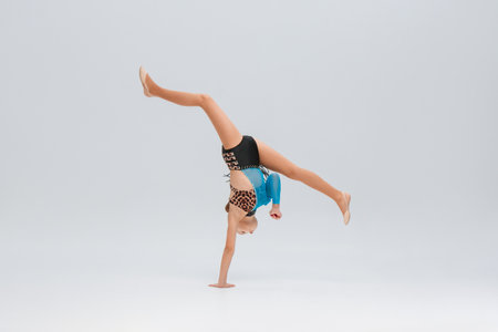 gymnast executes a flawless horizontal split in a handstand, balancing power and grace. Her outfit...