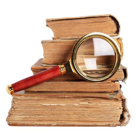Stack of books and magnifying glass isolated on white backgroundの写真素材