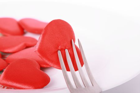 Red heart pierced by fork on the plateの写真素材