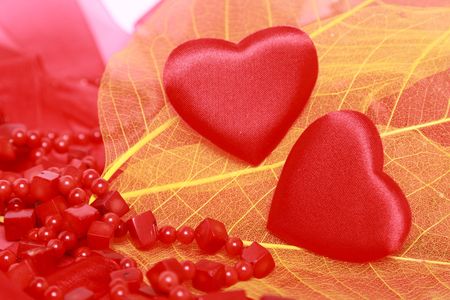 Red hearts and coral beads on leavesの写真素材
