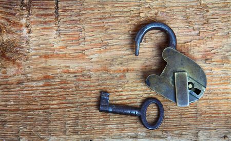 Old padlock and key on wooden backgroundの写真素材