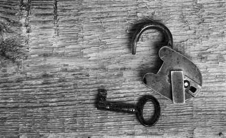 Old padlock and key on wooden background (black and white)の写真素材
