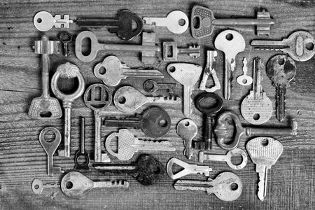 Old different keys on wooden board (black and white)の写真素材