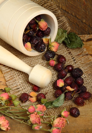 Wooden mortar and scattered rose hips on the sackingの写真素材