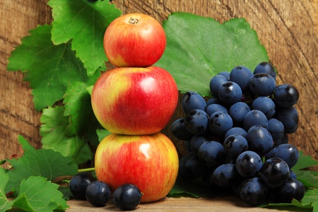 Three apples and bunch of grapes on wooden backgroundの写真素材