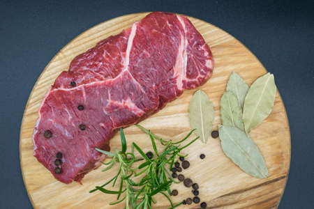 Beef steak, view of fresh beef on a wooden board with rosemary, black pepper, lavatory leaf.の写真素材