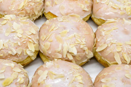 A close-up view of delicious donuts with icing and almond sprinkles.の写真素材