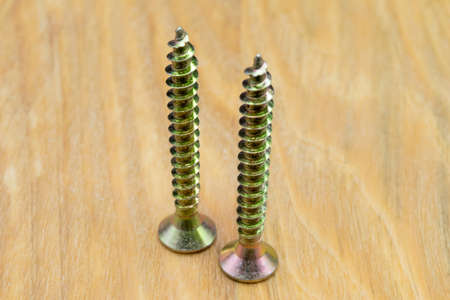 Metal screws for wood. Close-up view of metal wood screws on a wooden background.の写真素材