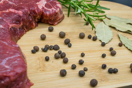 Beef steak, view of fresh beef on a wooden board with rosemary, black pepper, lavatory leaf.の写真素材
