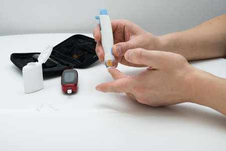 Closeup of young man using lancelet on finger in bathroomの写真素材