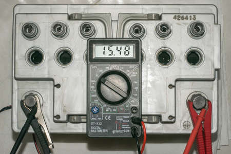 Car battery charging. Gray battery with caps unscrewed, charger cables connectedの写真素材