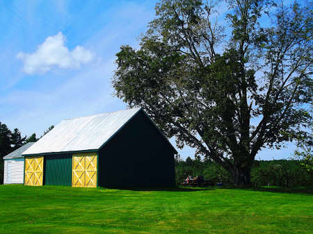 A family picnics next to a barn on a summer's day