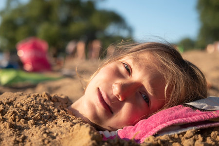 Young girl covered in sand on the beach. Head close-up.の写真素材