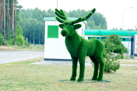 The figure of a deer made of artificial grass to attract tourists against the background of a partially forest is out of focus.の写真素材