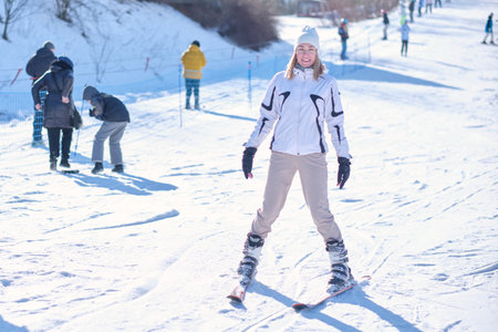 A woman of model appearance on skis against the background of an artificial descent track