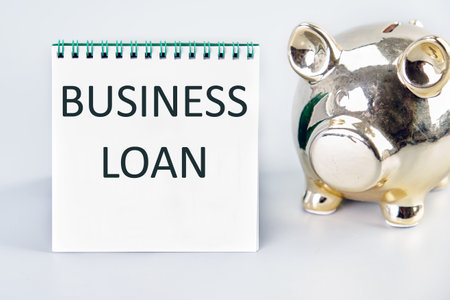 BUSINESS LOAN A word, a text written on a white sheet next to a piggy bankの写真素材