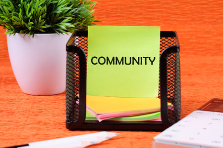 The word Community written on a green sticker next to office supplies on an orange backgroundの写真素材