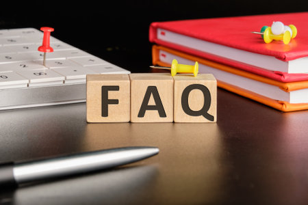 FAQ TEXT the text of non-wooden cubes next to notepads, a calculator, a pen on a black backgroundの写真素材