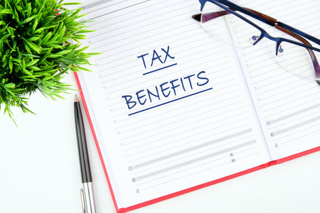 The concept of finance and business. TAX BENEFITS written in a notebook on the tableの写真素材