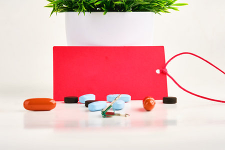 A red card on a white background. There are pills nearby. A place to copy. Concept photoの写真素材