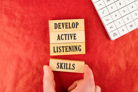 Concept word Develop active listening skills. Wooden blocks. Beautiful red background. The businessman's hand. The concept of business and brand. Space for copying.の写真素材