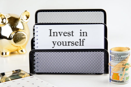 invest in yourself word on a white notepad with money and a piggy bank in the background out of focusの写真素材