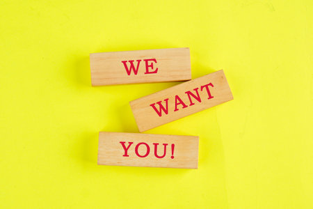 We want you on wooden blocks on a yellow background. Business conceptの写真素材