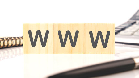WWW written on wooden cubes in a composition with a calculator, a pen on a white backgroundの写真素材