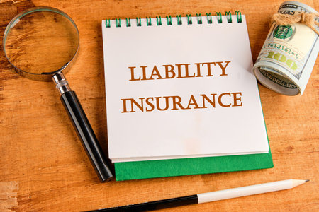 Text Liability Insurance on a notebook with a magnifying glass and a roll of money on a papyrus...