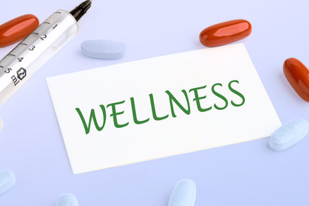 Wellness - word concept written on the business card next to pills, vitamins and a syringe