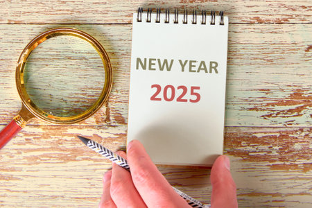 Business concept. NEW YEAR 2025 the inscription on the notebook holding the hand near the magnifying...
