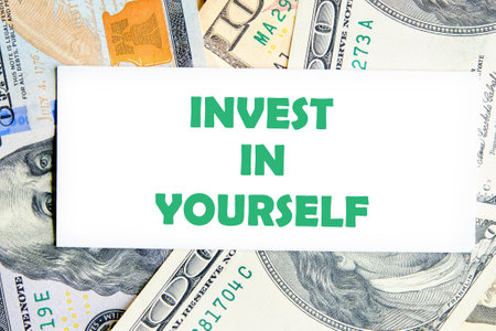 Education and self-motivation concept. Invest In Yourself words on a white business card against a...