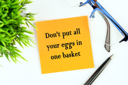 Don't put all your eggs in one basket text on a yellow sticker on a light background next to...