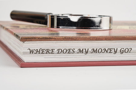 Question WHERE DOES MY MONEY GO on a book with a magnifying glass on top on a white background