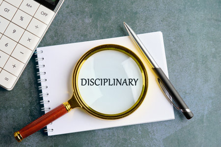 Word or phrase DISCIPLINARY written through a magnifying glass on a notebook in a composition with a...