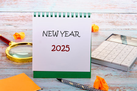 Business concept. NEW YEAR 2025 on a blank sheet of notepad next to a calculator, stickers, a...