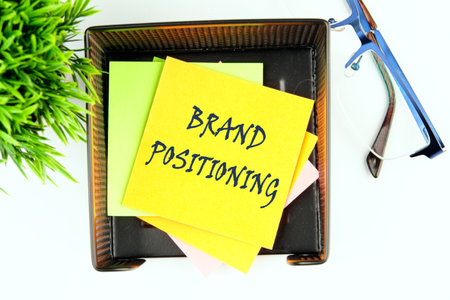 Business branding concept. BRAND POSITIONING text on a yellow sticker in a stand on a white...