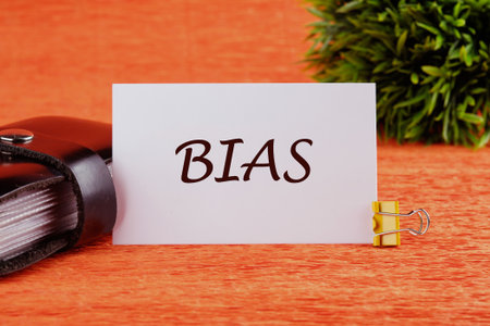 Research and analysis concept. Bias text, word on a white card in front of an orange background with a plant in the backgroundの写真素材