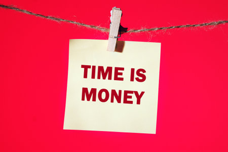 Stock market concept,TIME IS MONEY written on a yellow sticker suspended from a rope in front of a...