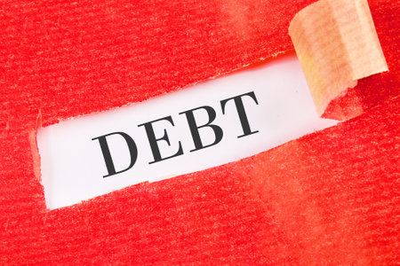Concepts of liabilities and taxes. DEBT written under the torn paper on a white background