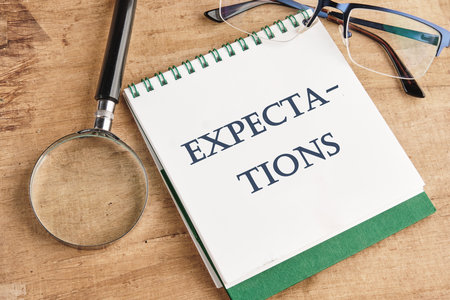 inscription Expectations word on a notebook in a composition with a magnifying glass, glasses and a...