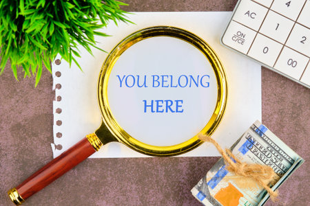 YOU BELONG HERE TEXT through a magnifying glass in a composition with American dollars, a calculator...